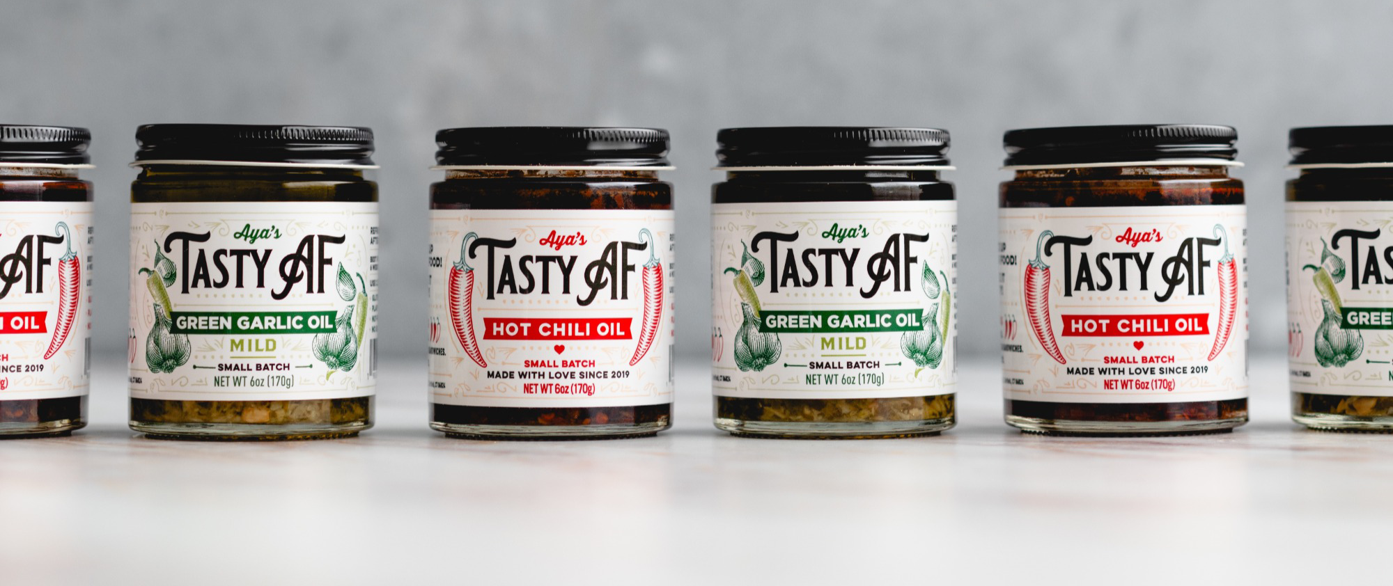 Aya's Tasty AF green garlic oil jars and hot chili oil jars